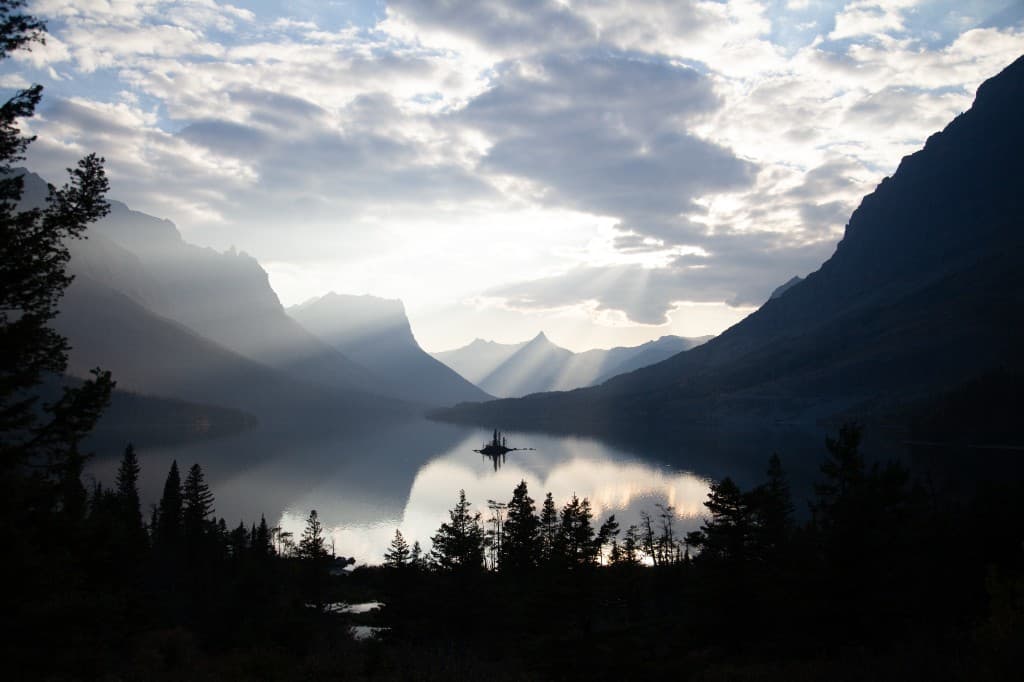 majestic mountain lake at sunrise with sun rays through clouds, glacial landscape, cinematic nature
